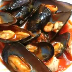 Un invitante piatto di zuppa di cozze al pomodoro, con cozze succulente immerse in un ricco sugo rosso.