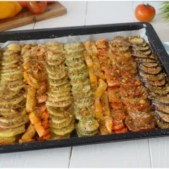 Vassoio con verdure al forno saporite disposte a raggiera: zucchine, carote, peperoni, pomodori e melanzane, condite con pangrattato.