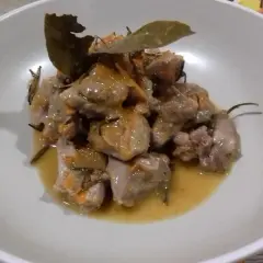 Delizioso spezzatino di tacchino in umido, con erbe aromatiche e una foglia di alloro, servito in una ciotola bianca.