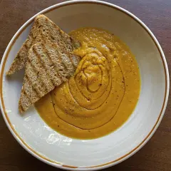 Vellutata di zucca cremosa, guarnita con pepe nero e accompagnata da crostini integrali tostati. Un comfort food perfetto.