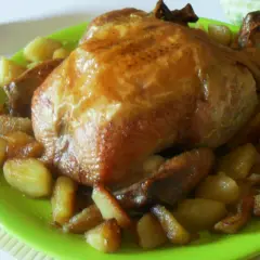 Un succulento pollo allo spiedo dorato, servito su un piatto verde brillante con patate arrosto.