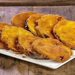 Fette di melanzane fritte solo con farina, dorate e croccanti, servite su un piatto bianco.