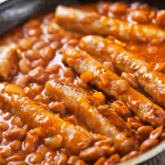 Salsiccia e fagioli in padella, un piatto confortante e saporito, con le salsicce dorate immerse in un letto di fagioli rossi in salsa.