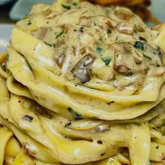 Un nido di tagliolini al tartufo cremosi, conditi con funghi e prezzemolo fresco.
