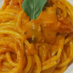 Un piatto invitante di pasta con i pomodorini, condita con una salsa cremosa e guarnita con una foglia di basilico fresco.