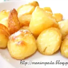 Un mucchio invitante di patate al forno dorate e croccanti, cosparse di un leggero velo di sale.