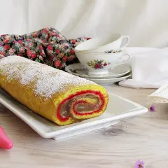 Rotolo dolce spolverato di zucchero a velo, un vero salame del re, con ripieno cremoso e bordi rossi.