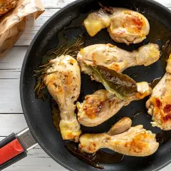 Cosce di pollo in padella, dorate e succulente, con rosmarino e alloro. Accompagnate da panini integrali.
