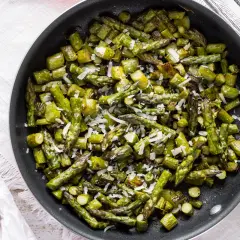 Asparagi verdi in padella, saltati e cosparsi di parmigiano grattugiato, pronti per essere gustati.