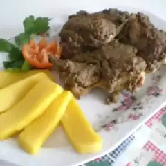 Piatto di coniglio in bianco con polenta e guarnizione di pomodoro e prezzemolo.