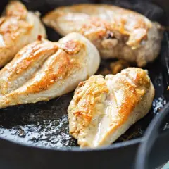 Petto di pollo dorato e succulento che sfrigola in padella, pronto per essere gustato.