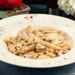 Piatto di pasta del pastore con crema, pollo e formaggio grattugiato, guarnito con paprika.