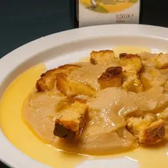 Piatto di crema di parmigiano con crostini dorati e un filo d'olio.