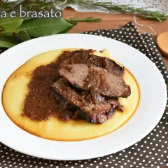 Piatto di polenta cremosa con fette di brasato di manzo succulento e salsa scura.