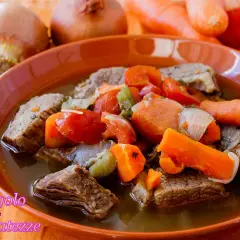 Un invitante brodo di carne con pezzi succulenti, carote, pomodori e cipolle. Un piatto caldo e confortante, perfetto per le giornate fredde.