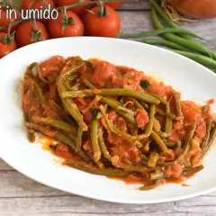Fagiolini in umido, un piatto saporito con fagiolini verdi cotti in un sugo di pomodoro e cipolla, accompagnato da pomodorini freschi.