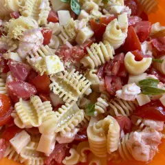 Pasta fredda con pomodoro, mozzarella, gamberetti e scorza di limone, un piatto estivo perfetto.