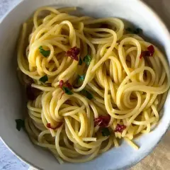 Spaghetti conditi con aglio, olio e peperoncino, guarniti con prezzemolo fresco. Un classico piatto italiano.