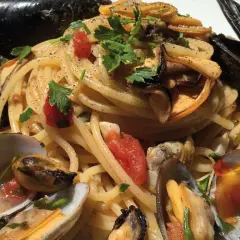 Spaghetti con cozze e vongole, un piatto cremoso e saporito, guarnito con prezzemolo fresco e pomodorini.