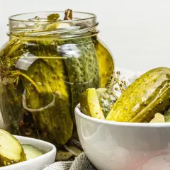 Vaso di cetriolini in agrodolce, con alcuni in una ciotola. Profumo di aneto e spezie.