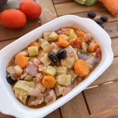 Un invitante piatto di caponata di verdure, con melanzane, carote, sedano e olive nere, pronto per essere gustato.