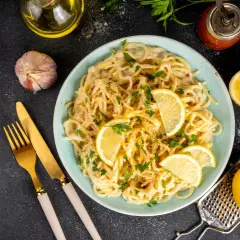 Spaghetti cremosi con un profumo agrumato, guarniti con spicchi di limone fresco e prezzemolo. Un piatto di pesto al limone che invita a gustare la freschezza.