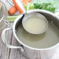 Un fumetto di pesce, filtrato in un colino, con verdure e brodo pronto in pentola.