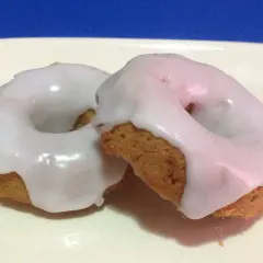 Due ciambelle con glassa per biscotti che si asciuga subito, su un piatto bianco.