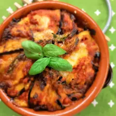 Deliziosa pasta alla norma al forno, con melanzane, pomodoro e basilico fresco, servita in una terrina di terracotta.