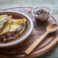 Crepes ripiene di una golosa nutella fatta in casa, pronte per essere gustate con un cucchiaino di legno.