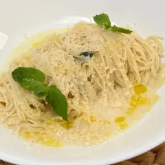 Spaghetti al limone cremosi, conditi con parmigiano e guarniti con menta fresca. Un piatto invitante e profumato.