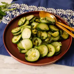 Zucchine trifolate bimby, un contorno semplice e gustoso, servite su un piatto marrone con cucchiai dorati.