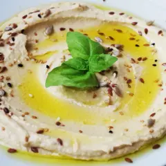 Hummus cremoso con semi misti e basilico, perfetto per idee pranzo veloci e gustose.
