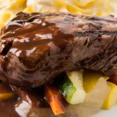 Succulento brasato al vino rosso su un letto di verdure miste e pasta all'uovo.