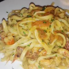 Un piatto invitante di tagliolini agli scampi, con pasta fresca e succulenti crostacei in una cremosa salsa, guarnito con prezzemolo tritato.