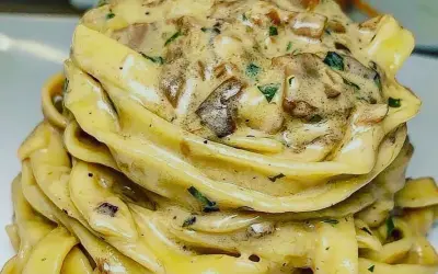 Un nido di tagliolini al tartufo cremosi, conditi con funghi e prezzemolo fresco.