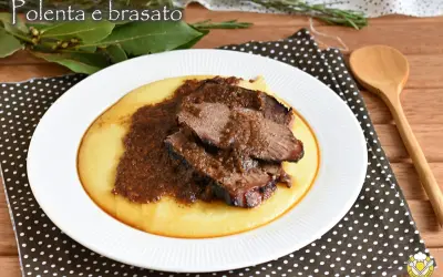 Piatto di polenta cremosa con fette di brasato di manzo succulento e salsa scura.