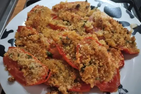 Pomodori gratinati al forno, un piatto saporito con pangrattato croccante e erbe aromatiche.