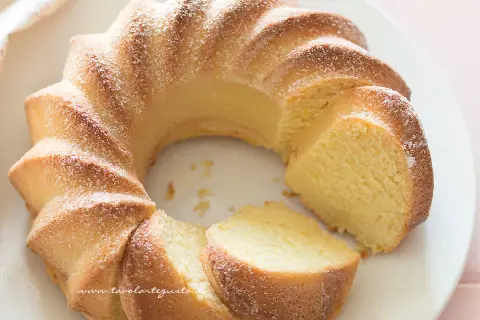 Deliziosa torta di ricotta, soffice e profumata, spolverata di zucchero a velo su un piatto bianco.
