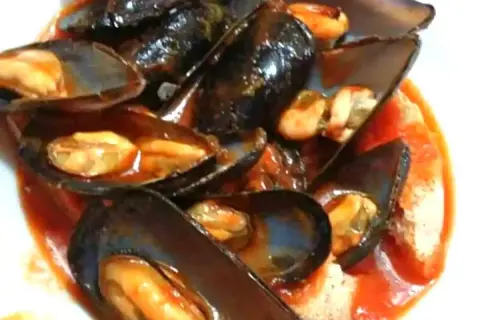 Un invitante piatto di zuppa di cozze al pomodoro, con cozze succulente immerse in un ricco sugo rosso.