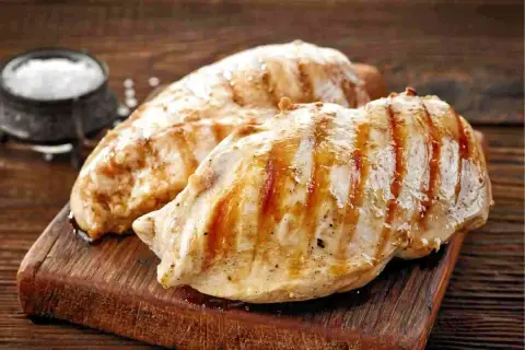 Petto di pollo grigliato, perfetti secondi di carne da preparare in anticipo. Un contorno di sale completa l'immagine.