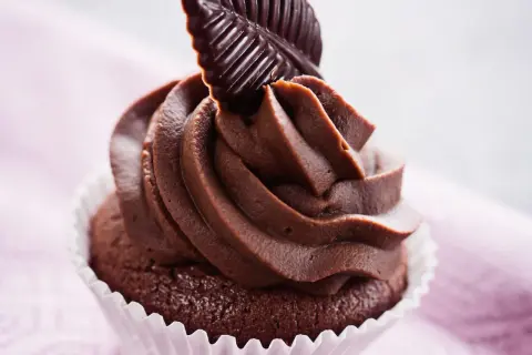 Un goloso cupcake al cioccolato con glassa cremosa e una decorazione a forma di foglia di cioccolato fondente.