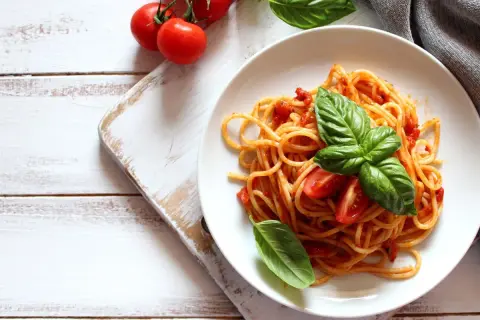 Spaghetti conditi con sugo di pomodoro fresco e basilico, guarniti con pomodorini. Un piatto semplice e gustoso.