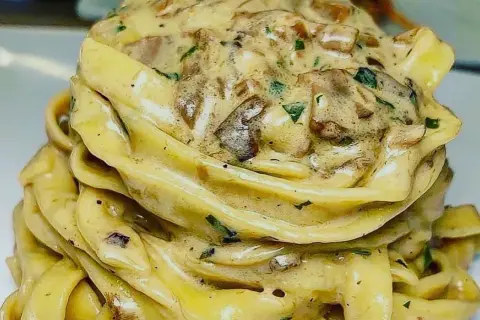 Un nido di tagliolini al tartufo cremosi, conditi con funghi e prezzemolo fresco.