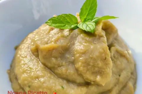 Un cremoso pesto di melanzane, guarnito con foglie di menta fresca, pronto per essere gustato.