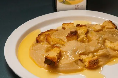 Piatto di crema di parmigiano con crostini dorati e un filo d'olio.