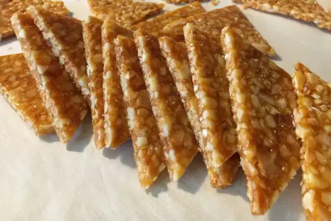 Fette triangolari di croccante di mandorle dorato, con mandorle tritate immerse in caramello lucido.