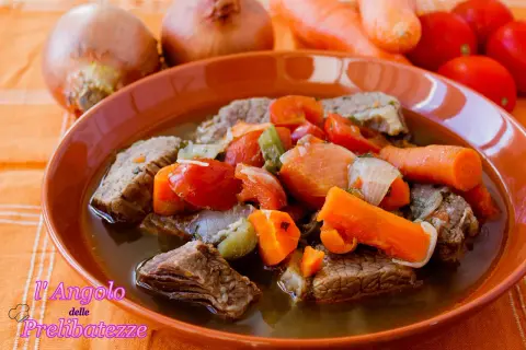 Un invitante brodo di carne con pezzi succulenti, carote, pomodori e cipolle. Un piatto caldo e confortante, perfetto per le giornate fredde.