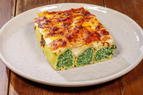 Crespelle alla fiorentina, rotoli di pasta ripieni di spinaci e ricotta, gratinati al forno con formaggio fuso.
