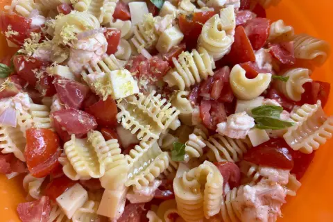 Pasta fredda con pomodoro, mozzarella, gamberetti e scorza di limone, un piatto estivo perfetto.